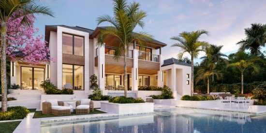 Modern two‑story tropical home at sunset with large glass windows, a pool, lounge chairs, and palm trees reflecting warm golden light.